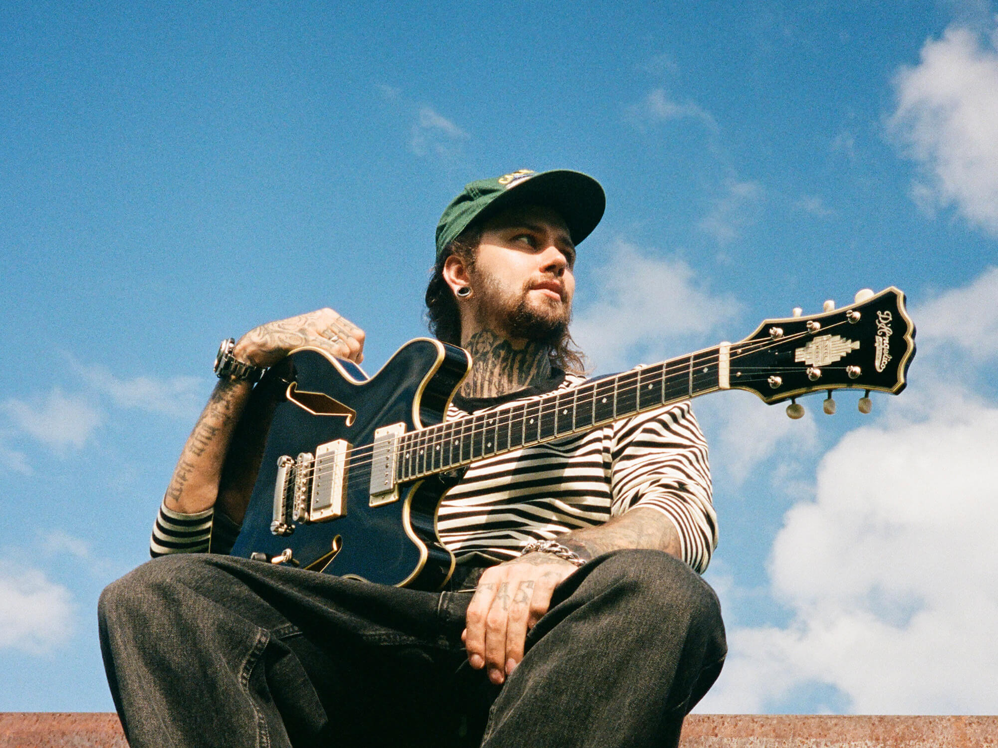 Roman Bulakhov photographed with a guitar against a blue sky, photo by Kostya Borovski